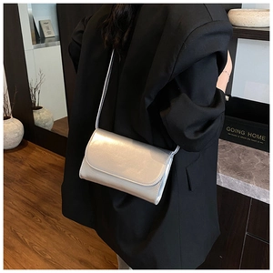 Detailopname van een zilveren crossbodytas met spiegeleffect op een zwarte blazer