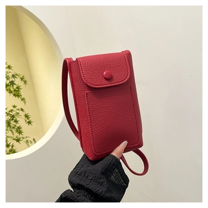 Detail view of red lychee textured leather mini crossbody phone bag with round buckle