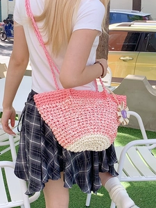 Pink and beige woven tote bag with 3D flower charm on shoulder of a model