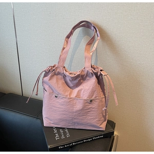 Detail of dusty pink nylon tote bag showing drawstring closure and silver buckles