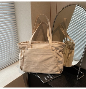 Détail du grand sac cabas en nylon crème avec poche frontale et plis latéraux de style