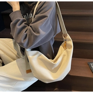 Detail of off-white canvas hobo bag with zipper on wooden stairs in warm lighting