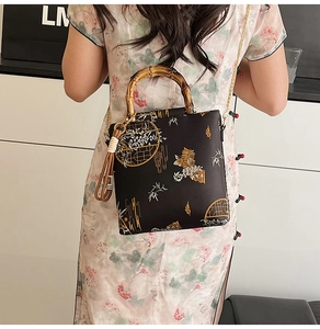Detail of black brocade handbag with bamboo handle, gold chain, and floral embroidery
