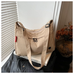 Close-up of lightweight nylon crossbody bag with adjustable strap and red woven label