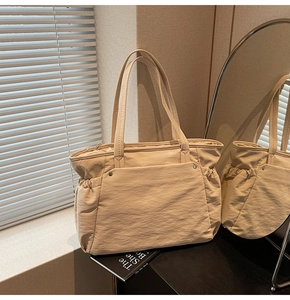 Détail d'un grand sac cabas beige avec poche frontale et plis pour le trajet quotidien