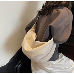 Detail view of beige canvas hobo bag showing minimalist croissant pleated texture