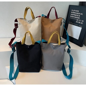Détail de grands sacs fourre-tout en toile en quatre couleurs avec bandoulières contrastées