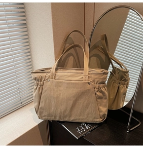 Détail du grand sac cabas kaki avec poche à rivets et design latéral élastique plissé
