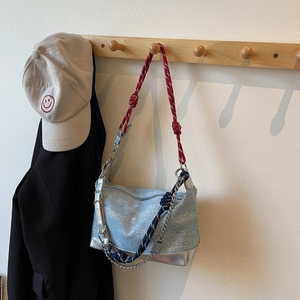 Close-up of light blue denim tote bag with red rope strap hanging on a wooden hook