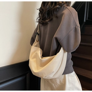 Detail shot of a cream canvas crescent crossbody bag with adjustable black strap