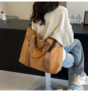 Rear view of model wearing a large ginger nylon tote bag with adjustable shoulder strap