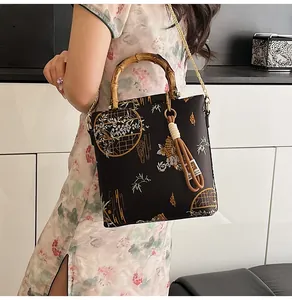 Detail of bamboo handle and traditional floral embroidery on a black satin handbag