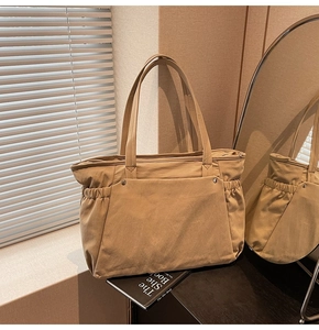 Détail d'un grand sac fourre-tout en nylon avec poche avant, rivets et fermeture