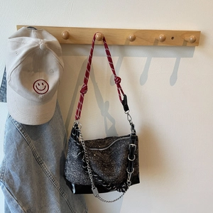 Detail of a black sequin shoulder bag with colorful rope strap and silver chain accent