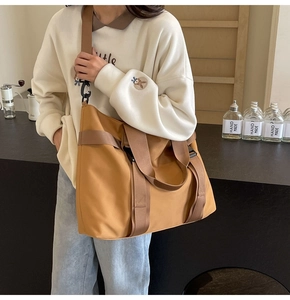 Close-up of a large camel canvas tote bag showing durable straps and functional buckle