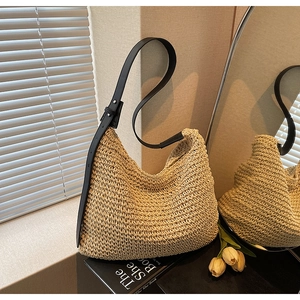 Dettaglio borsa tote in paglia intrecciata con tracolla nera in luce naturale soffusa
