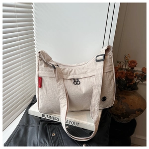 Detailed shot of a beige nylon crossbody bag with adjustable strap on a book background