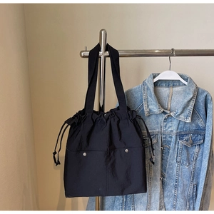 Detail of black nylon drawstring tote bag hanging with blue denim jacket for casual look