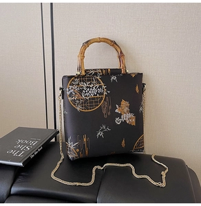 Detailed close-up of a vintage bamboo handle and gold chain on a Chinese-style handbag