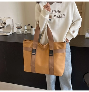 Detailed view of ginger canvas tote bag with black buckle closure in a cafe setting