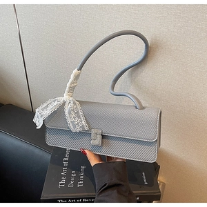 Dettaglio della borsa grigia con manico a onde e fiocco in pizzo bianco elegante