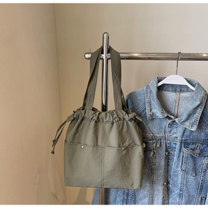 Army green nylon tote bag featuring front utility pockets and adjustable drawstring closure