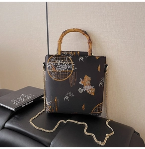 Detailed view of black bag with oriental embroidery, bamboo handle and gold chain
