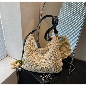 Dettaglio della texture della borsa tote in paglia con tracolla in pelle nera e fibbia