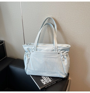Détail du grand sac cabas bleu clair avec poche à rabat à rivets et fermeture éclair