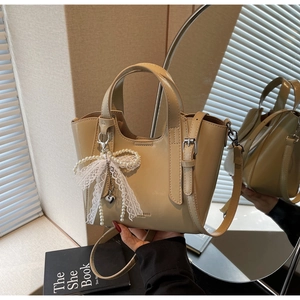 Detail of khaki leather bucket bag with lace pearl bow and gold heart pendant