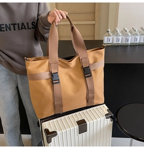 Close-up of large khaki canvas tote bag with functional buckle straps on luggage