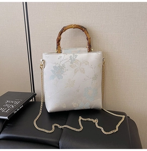 Detail of floral jacquard handbag featuring bamboo handle and golden chain strap