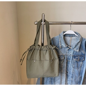 Detail of olive green drawstring tote bag showing fabric texture and front pockets