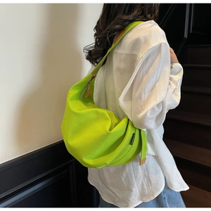 Detail of bright green canvas hobo bag with zip leather puller and side brand label