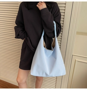 Close-up of light blue textured shoulder bag with spacious interior and coffee-colored lining
