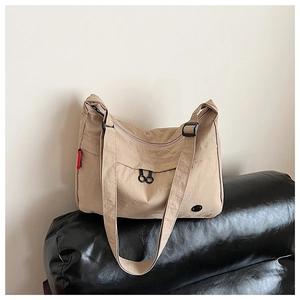 Detail view of khaki nylon shoulder bag with adjustable strap and side red tag