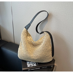 Dettaglio della borsa hobo in paglia intrecciata con tracolla nera in ecopelle