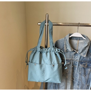 Detail of blue nylon drawstring bucket bag showing metal snap buttons and texture