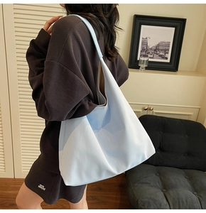 Side view of large gradient blue tote bag worn by model in a cozy indoor setting
