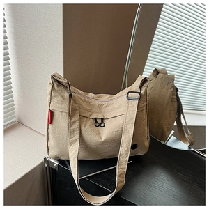 Close-up of khaki nylon messenger bag with dual zipper pockets and adjustable shoulder strap