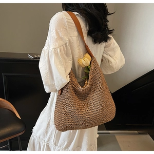 Dettaglio di una borsa in paglia con tracolla in pelle e fiori su un vestito di pizzo