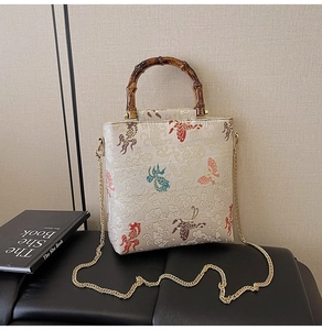 Detail of beaded lace handbag featuring oriental embroidery and bamboo handle