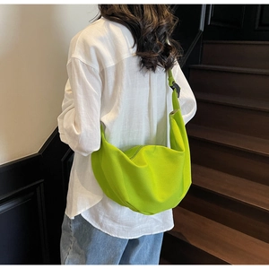 Detail of neon green canvas crescent bag showing large capacity and adjustable strap