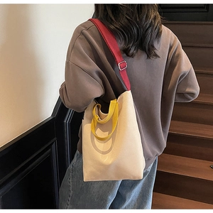 Détail du sac fourre-tout en toile bicolore avec bandoulière rouge et poignée jaune ici