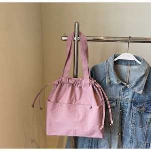 Detail of mauve nylon bucket bag featuring a drawstring closure and silver metal rivets