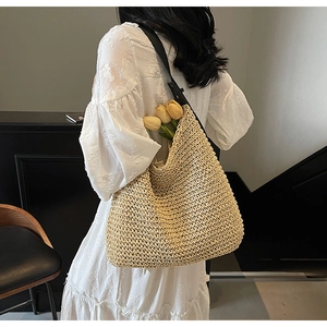 Dettaglio di borsa tote in paglia intrecciata con spalline in pelle nera e trama