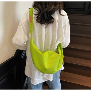 Neon green canvas crossbody bag detail showing leather patch and stylish pleated texture