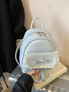 Hellblauer Mini-Rucksack mit Spitzenbesatz und Schleife auf einem Stapel Vintage-Bücher