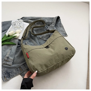 Detail of olive green nylon crossbody bag with textured fabric and red side label