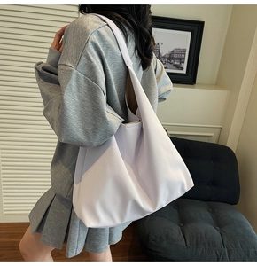 Large crescent tote bag in pale beige with horizontal texture on model shoulder